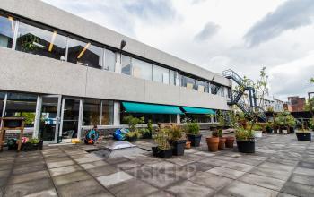 Exterior of an office building located at Zomerhofstraat 84, Rotterdam North, with a large open terrace area and greenery.