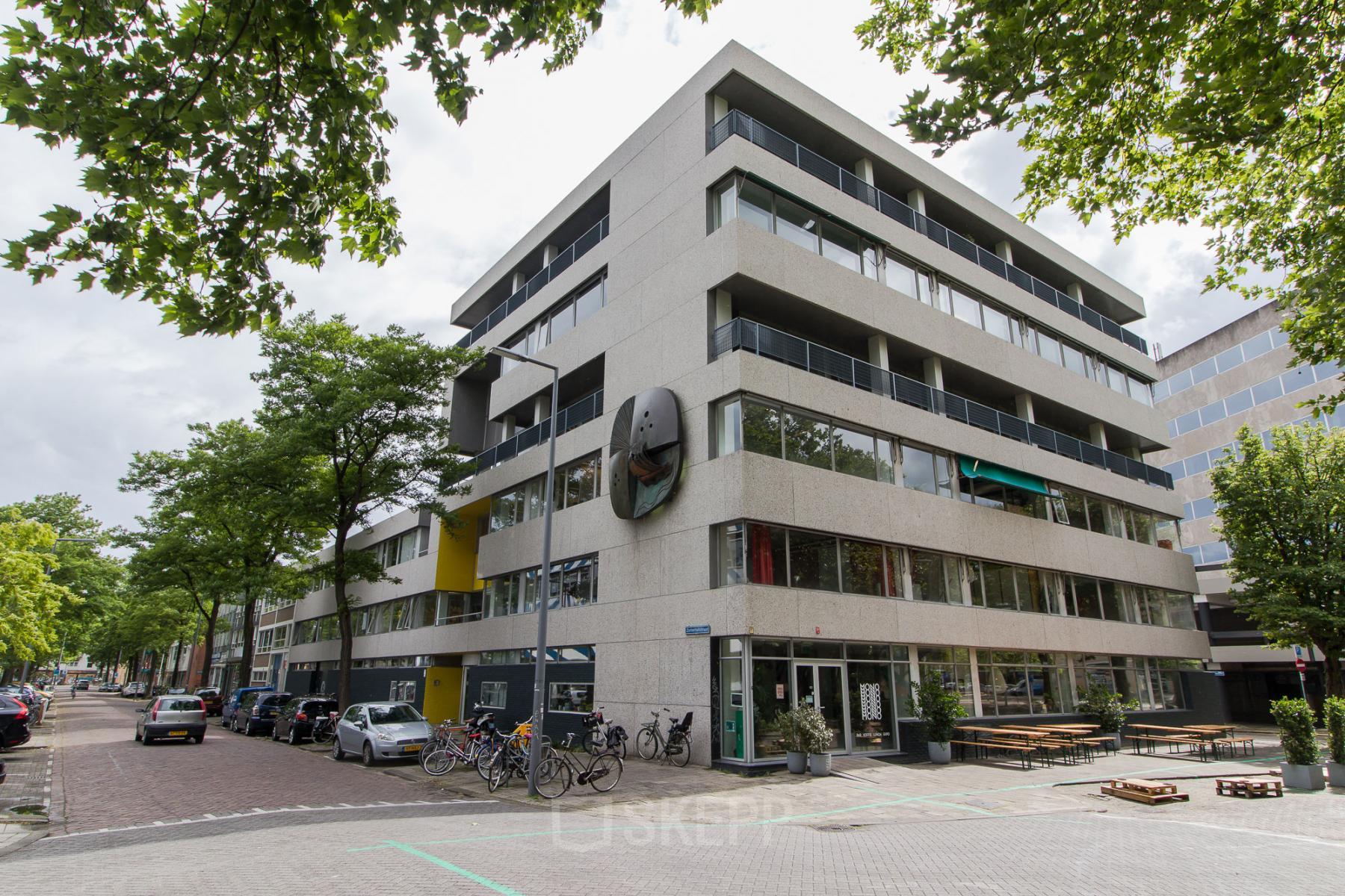 Exterior view of the office building at Zomerhofstraat 84, Rotterdam North, highlighting multiple floors with balconies and street parking available nearby.