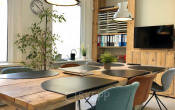 Modern office space rental at Van der Takstraat 8, Rotterdam Noordereiland, featuring a wooden table, comfy chairs, and ample natural light.