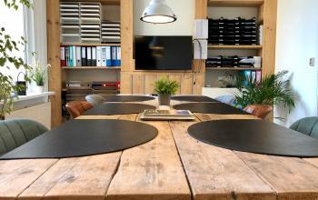 Modern office space rental at Van der Takstraat 8, Rotterdam Noordereiland with a large wooden table and plush seating.