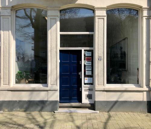 Charming blue door entryway of office space rental at Van der Takstraat 8, surrounded by large windows in Rotterdam Noordereiland.
