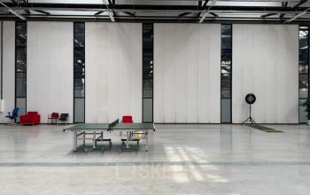 Spacious interior at Scheepsbouwweg 29 in Rotterdam Waalhaven, highlighting an industrial aesthetic with a ping pong table and scattered seating. Perfect office space rental for innovative activities.