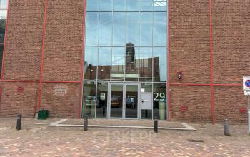 Exterior view of the office building at Scheepsbouwweg 29, Rotterdam Waalhaven, showcasing a modern glass entrance suitable for those seeking office space rental.