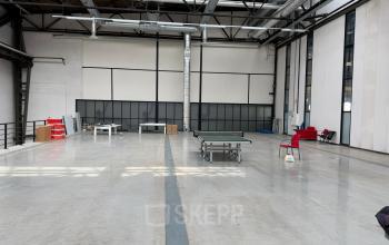 Spacious office area available for rent in Rotterdam Waalhaven, featuring high ceilings, large windows, and minimal furnishings, ideal for versatile workspace configurations.