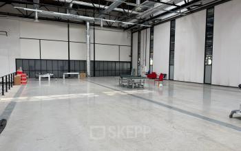 Spacious industrial-style office space to rent at Scheepsbouwweg 29, Rotterdam Waalhaven, featuring high ceilings, large windows, and minimal furnishings.
