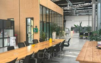 Spacious industrial-style interior at Scheepsbouwweg 29, Rotterdam Waalhaven, featuring a long wooden table and chairs suitable for collaborative work. Ideal for office space rental.