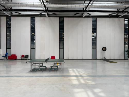 Spacious interior at Scheepsbouwweg 29 in Rotterdam Waalhaven, highlighting an industrial aesthetic with a ping pong table and scattered seating. Perfect office space rental for innovative activities.