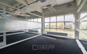 Modern office space with large windows, plenty of natural light, and carpet flooring located at Overschieseweg 34 in Schiedam.