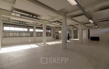 Spacious office to rent at Overschieseweg 34, Schiedam featuring large windows, industrial lighting, and open floor plan with ample natural light.