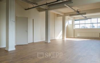 Spacious, well-lit office space with large windows and wooden flooring at Overschieseweg 34, Schiedam. Prime location for office space rental.