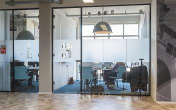 Office to rent at Overschieseweg 34, Schiedam featuring a modern workspace with glass partitions and blue chairs.