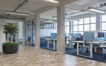 Modern furnished office space rental at Overschieseweg 34 in Schiedam, featuring spacious desks, large windows, and ample natural light.