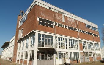 Exterior view of the office building located at Overschieseweg 34, Schiedam, showcasing a brick facade with multiple large windows.