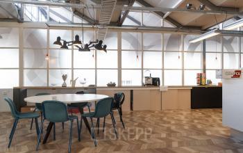 Chic office space rental at Overschieseweg 34, Schiedam with stylish furniture, a round table, modern lighting, and a pantry area.