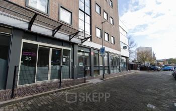 Exterior view of an office building at Noordvest 18, Schiedam, featuring several entry points along a brick-lined sidewalk.