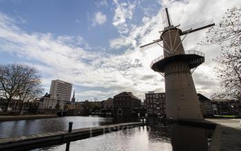 Exterior view of the windmill and surrounding area near Noordvest 18 in Schiedam, featuring traditional buildings and a scenic canal.