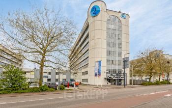 Exterior view of the office building at de Brauwweg 52-66 in Schiedam, showcasing modern architecture and ample parking. Ideal location for office space rental with great accessibility.