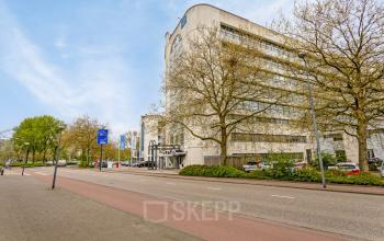 Exterior view of office space at de Brauwweg 52-66, Schiedam showing a multi-story building with trees along the street. Ideal location for renting office space.