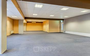 Spacious, unfurnished office space at de Brauwweg 52-66 in Schiedam, perfect for office space rental. The room features a neutral color palette and a carpeted floor.