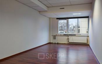Unfurnished office space with wooden flooring and large window at de Brauwweg 52-66, Schiedam, available for rent.