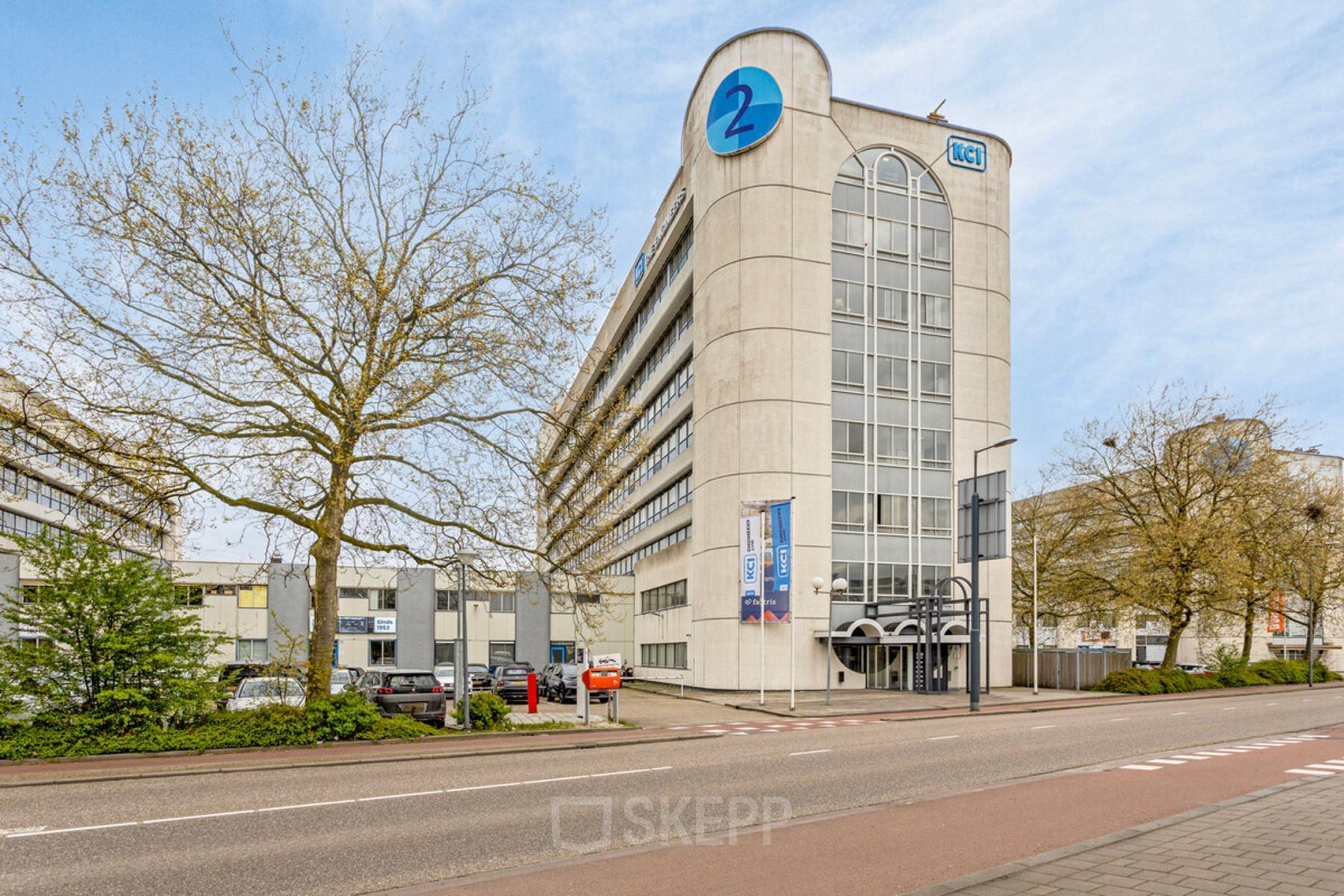 Exterior view of the office building at de Brauwweg 52-66 in Schiedam, showcasing modern architecture and ample parking. Ideal location for office space rental with great accessibility.