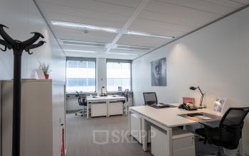 Office space rental at Schiphol Boulevard 127 featuring modern desks, chairs, and bright natural light from large windows.