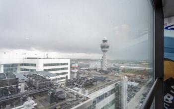 View from Schiphol Boulevard 127 at Schiphol Airport showcasing airport facilities and control tower through a window.
