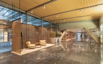 Spacious office to rent at Schiphol Boulevard 127, featuring stylish seating and modern decor under a high ceiling, ideal for office space rental.