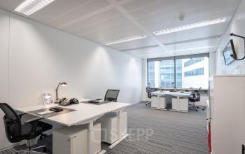 Modern office to rent at Schiphol Boulevard 127, featuring desks, chairs, and natural light through large windows.