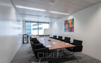 Modern conference room in Schiphol Airport with sleek furniture and a vibrant painting, suitable for office space rental. Located at Schiphol Boulevard 127.