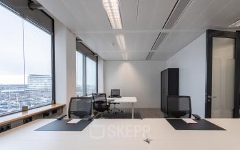Bright office space at Schiphol Boulevard 127, featuring large windows with city views and modern furnishings, available for office space rental.