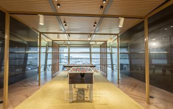 Modern furnished workspace at Schiphol Boulevard 127 featuring a foosball table, ideal for office space rental with panoramic airport views.