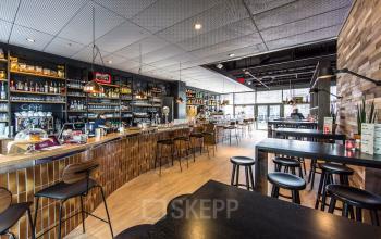 Modern office space rental at Evert van de Beekstraat 104, Schiphol with a cafe-style lounge and well-stocked bar area.