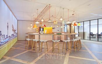 Modern furnished pantry area with a high countertop, bar stools, and pendant lights at Evert van de Beekstraat 104, Schiphol Airport, ideal for office space rental.