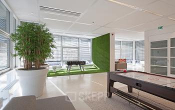 Office space for rent at Evert van de Beekstraat 104 in Schiphol Airport featuring bright windows, a foosball table, and a seating area.