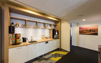 Modern pantry with coffee machines, sink, and storage shelves in an office located at Evert van de Beekstraat 310, Schiphol Airport.