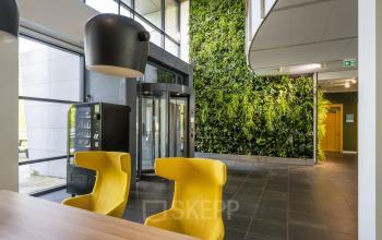 Modern entrance at Boeingavenue 223-239, Schiphol Rijk, Schiphol with a vertical garden and bright yellow chairs, perfect for office space rental.