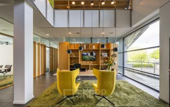 Modern office with yellow chairs, wall-mounted TV, and large windows at Boeingavenue 223-239, Schiphol Rijk. Ideal for office space rental.