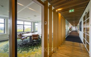 Interior view of office space at Boeingavenue 223-239, Schiphol Rijk, featuring modern workspaces and a hallway with wooden accents and green carpet.