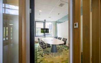 Conference room at Boeingavenue 223–239, Schiphol Rijk, featuring a round table, five office chairs, and a TV screen for presentations.