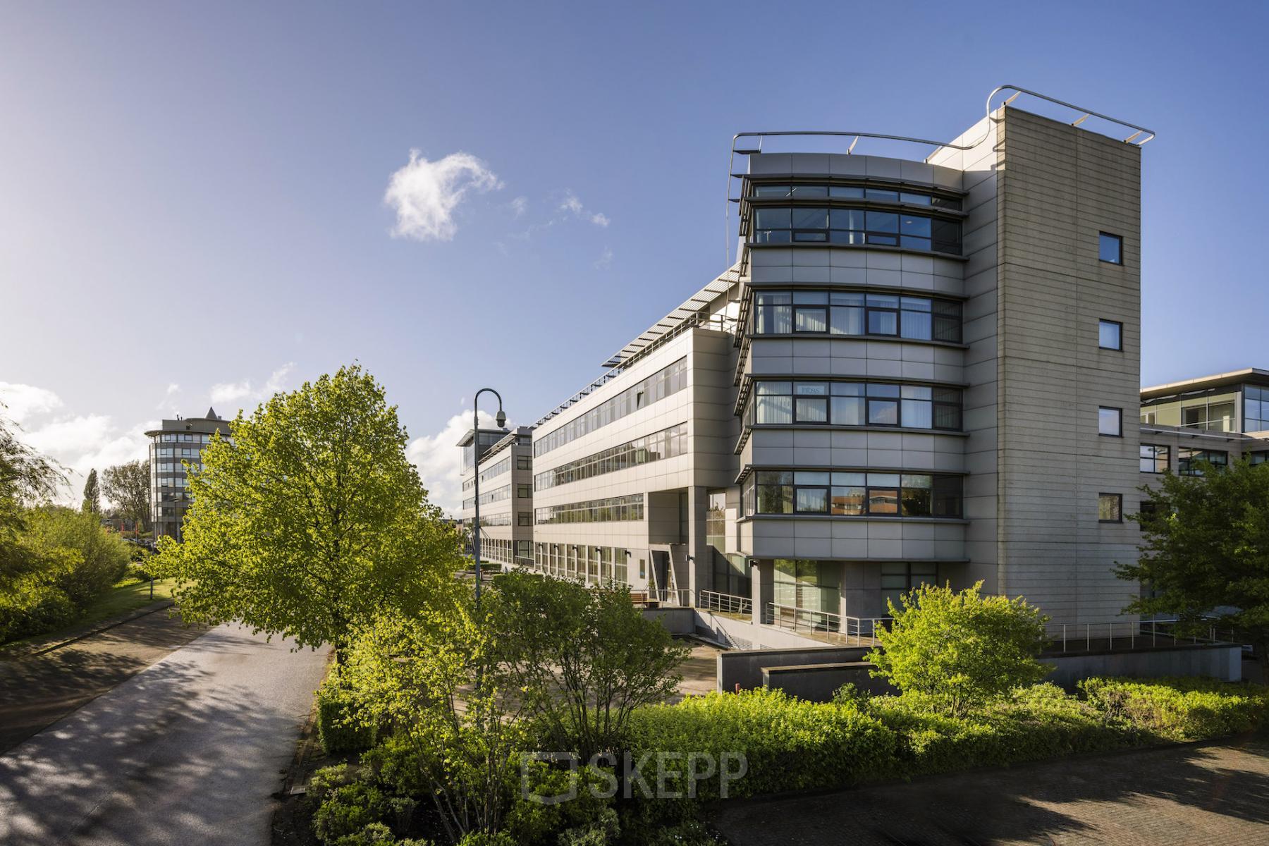 Modern office building located at Boeingavenue 223 – 239, Schiphol Rijk, with multiple stories and large windows, surrounded by green foliage, ideal for office space rental.