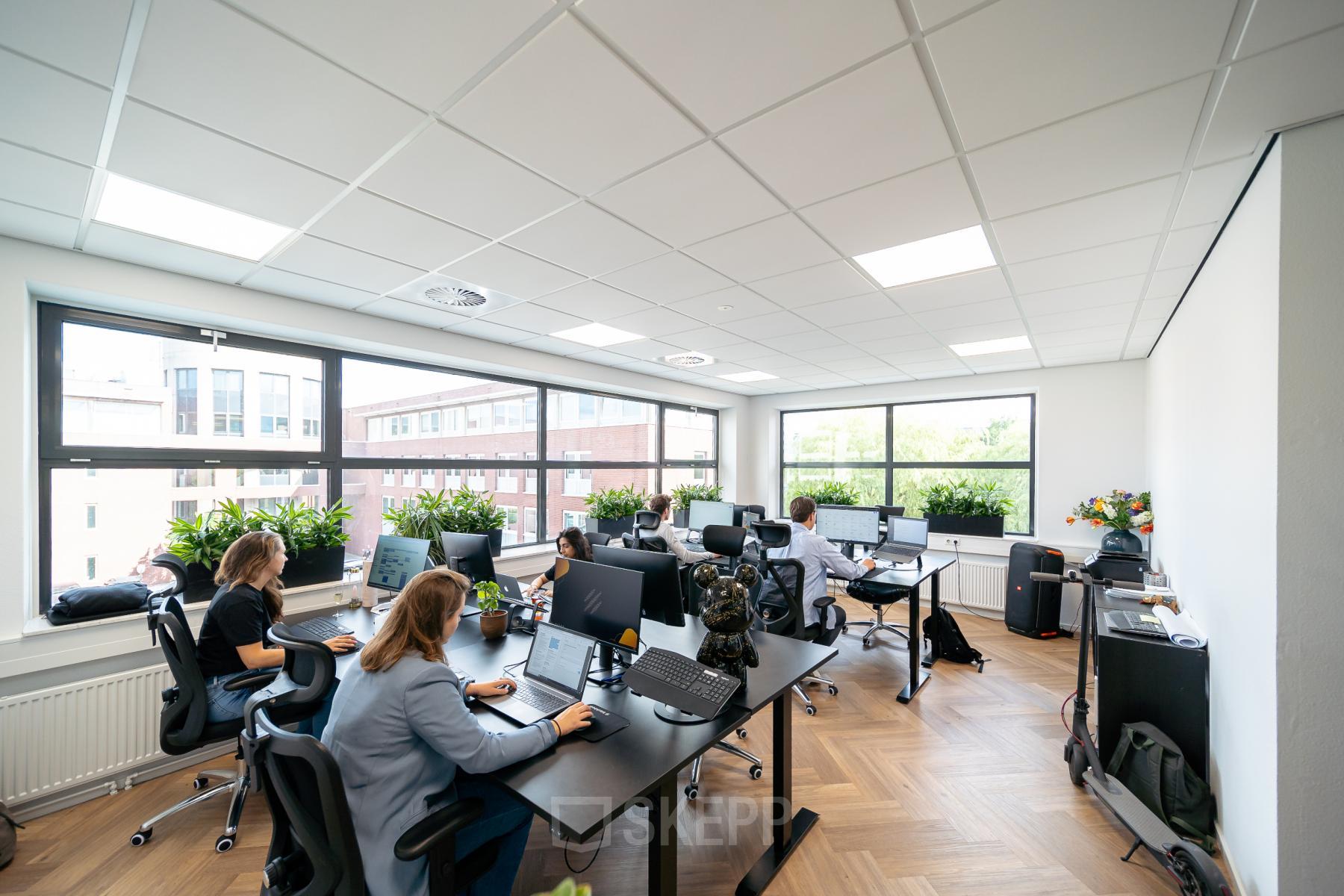 Modern workspace at Beechavenue 30, Schiphol Rijk, featuring desks with computers, abundant natural light, and people engaged in office activities.