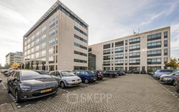 Exterior view of Beechavenue 54-62 office space rental in Schiphol, showcasing its modern facade and adjacent parking lot.