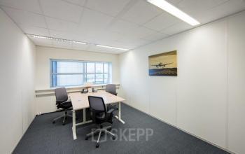 Modern office space rental at Beechavenue 54-62, Schiphol with a well-lit meeting room featuring a large table, chairs, and aviation-themed wall art.