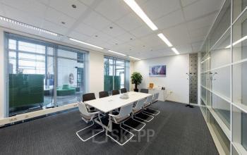 Modern conference room at Beechavenue 54-62, Schiphol with a long table, chairs, and a presentation screen, ideal for office space rental.