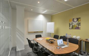 Vergaderruimte te huur op Keizer Karellaan 584 in Sint-Agatha-Berchem met lange houten tafel, vergaderstoelen en presentatiematerialen. Ideaal voor professioneel gebruik.