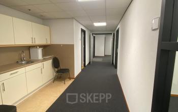 Bright hallway interior at 200 Milaanstraat, Sittard, featuring carpet flooring and a kitchenette area for convenient office space rental setup.