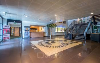 Spacious entrance area at 200 Milaanstraat, Sittard, showcasing a modern reception with a large logo on the floor, inviting as part of the office space rental offering.