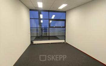 Well-lit office available for rent at 200 Milaanstraat, Sittard, featuring large windows and neutral carpeting, ideal for versatile office space rental needs.