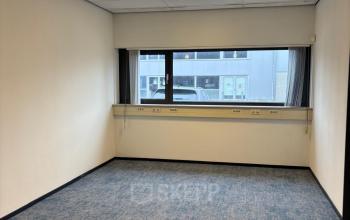 Unfurnished office space at Fischerpad 106 in Sittard available for rent, featuring blue carpet and wide windows.